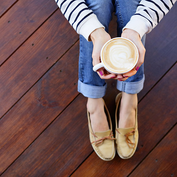 Woman sitting on hardwood floor holding a latte